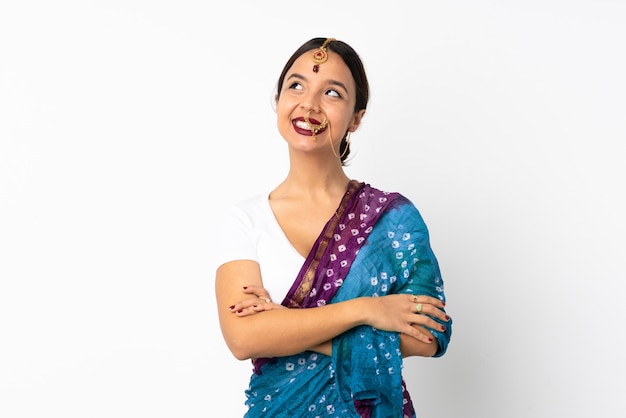 Young indian woman isolated on white wall looking up while smiling