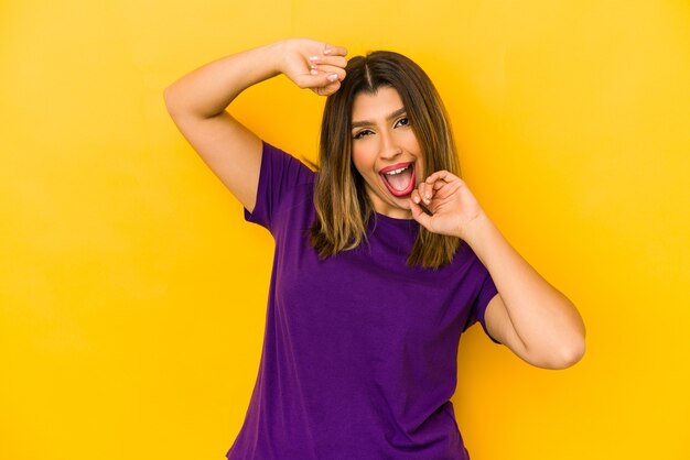 Photo young indian woman isolated on yellow background celebrating a special day, jumps and raise arms with energy.
