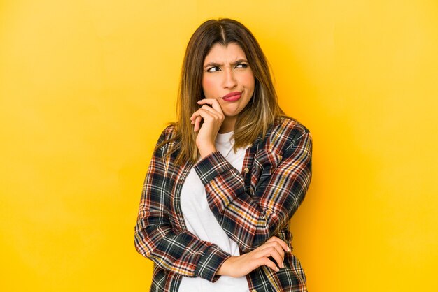 Young indian woman isolated on yellow background confused, feels doubtful and unsure.