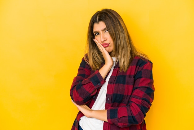 Young indian woman isolated on yellow wall contemplating, planning a strategy, thinking about the way of a business.