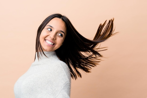 Young indian woman moving her hair isolated on beige background