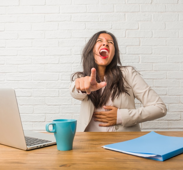 Young indian woman at the office shouting, laughing and making fun of another, concept of mockery and uncontrol