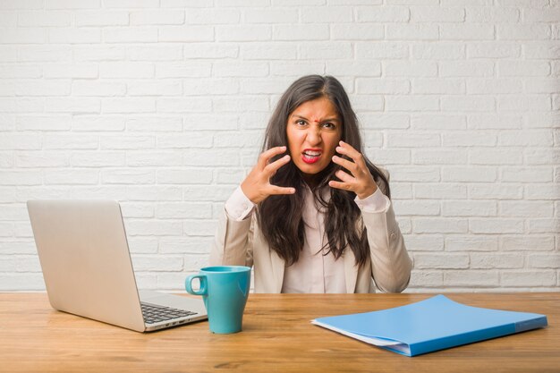 Young indian woman at the office very angry and upset, very tense, screaming furious