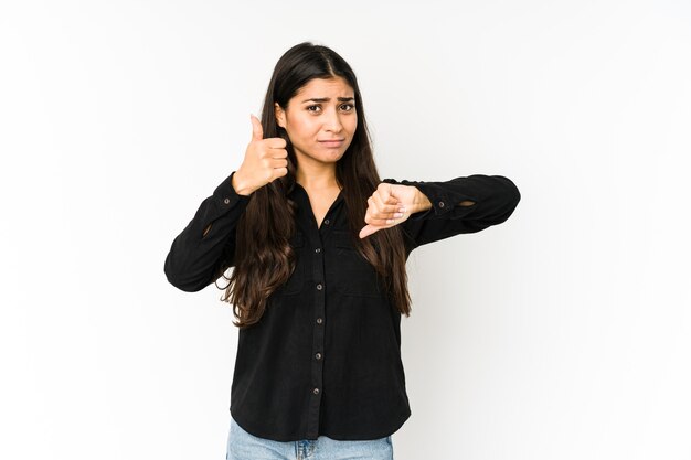 Young indian woman on purple showing thumbs up and thumbs down, difficult choose concept