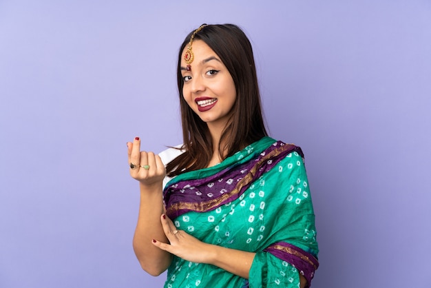 Photo young indian woman on purple wall making money gesture