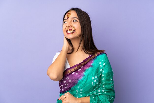 Young indian woman on purple wall thinking an idea