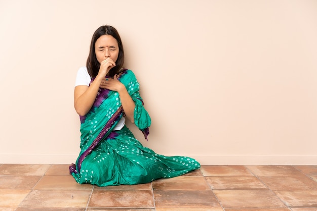 Young Indian woman sitting on the floor coughing a lot