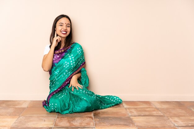 Young Indian woman sitting on the floor laughing