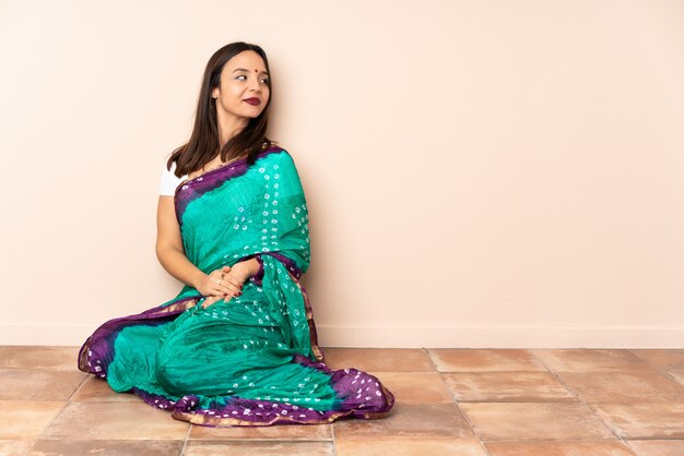 Young Indian woman sitting on the floor looking to the side