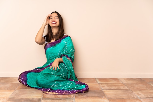 Photo young indian woman sitting on the floor smiling a lot