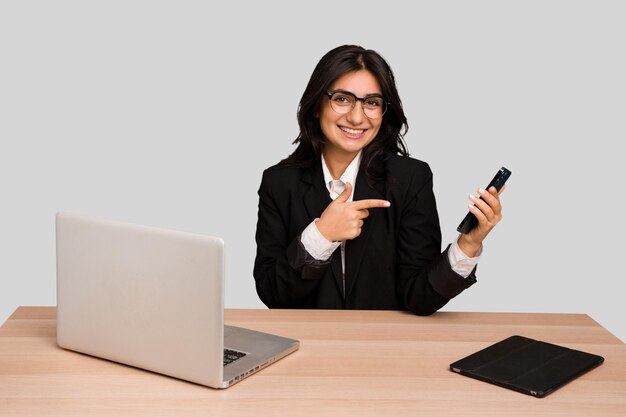 Young indian woman in a table with a laptop and tablet using a mobile phone isolated