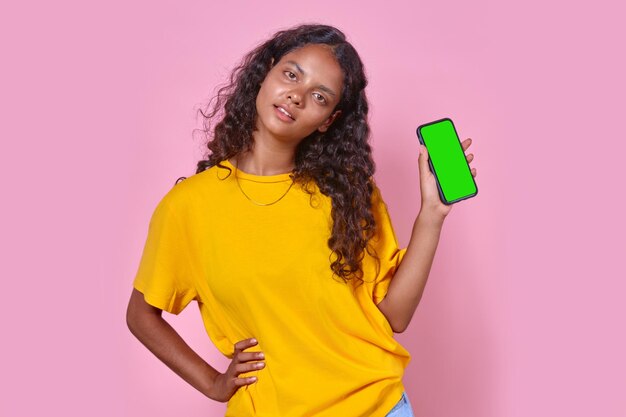 Young indian woman teen shows mobile phone with green screen stands in studio