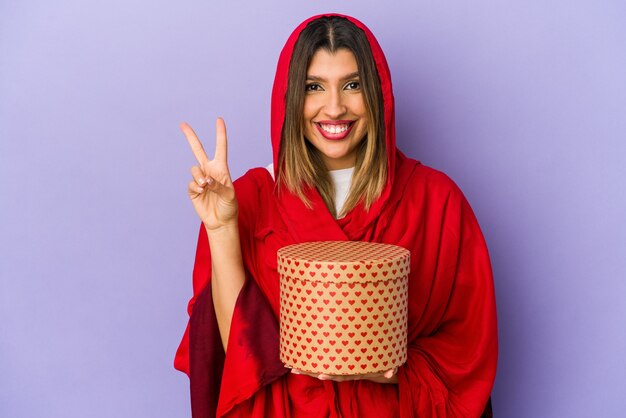 Young indian woman wearing a hijab holding a valentines day gift isolated showing number two with fingers.