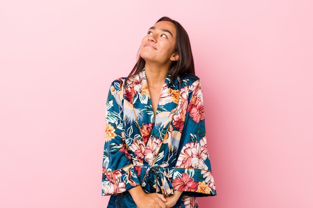 Young indian woman wearing a kimono pajama dreaming of achieving goals and purposes