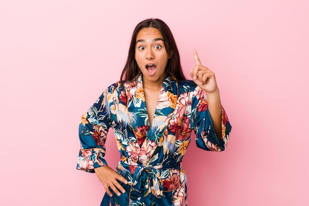 Young indian woman wearing a kimono pajama having an idea, inspiration concept.