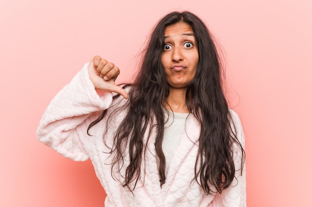 Young indian woman wearing pajama showing a dislike gesture, thumbs down. Disagreement concept.