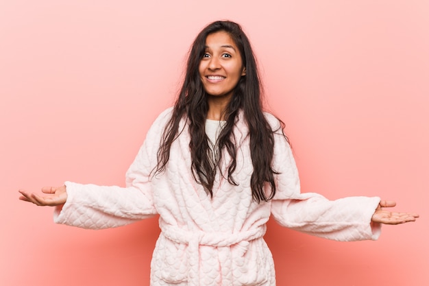 Young indian woman wearing pajama showing a welcome expression.