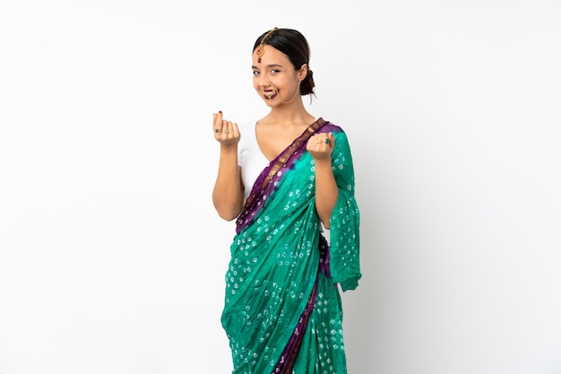 Young indian woman on white wall making money gesture