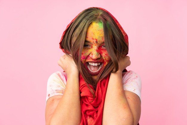 Giovane donna indiana con le polveri colorate di holi sul suo fronte isolato sulla parete rosa