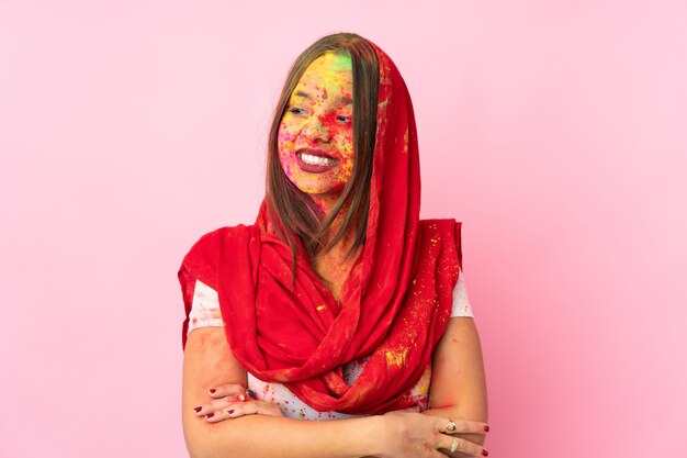 분홍색 벽에 그녀의 얼굴에 화려한 holi 분말을 가진 젊은 인도 여자는 측면을 찾고
