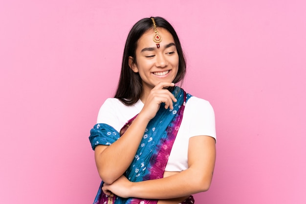 Молодая индийская женщина с сари через стену, глядя в сторону