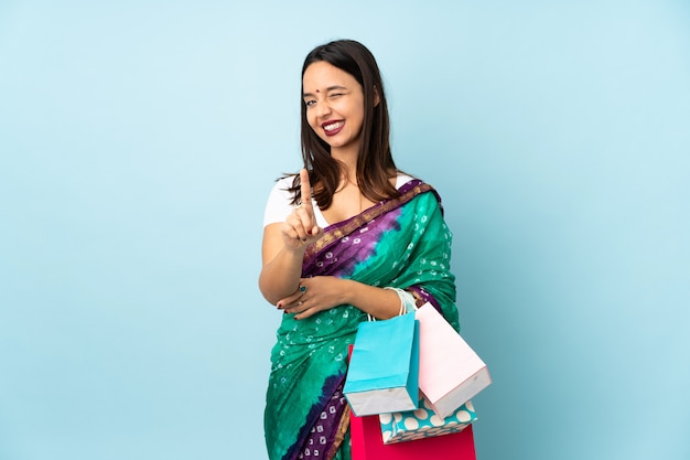 Young Indian woman with shopping bags showing and lifting a finger