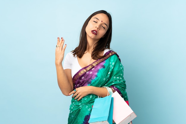 Young indian woman with shopping bags with tired and sick\
expression