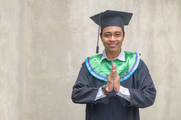 Photo young indonesian guys greeting pose when graduation moment