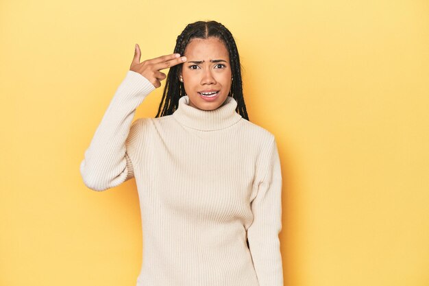 Foto giovane donna indonesiana sullo sfondo giallo dello studio che mostra un gesto di delusione con l'indice