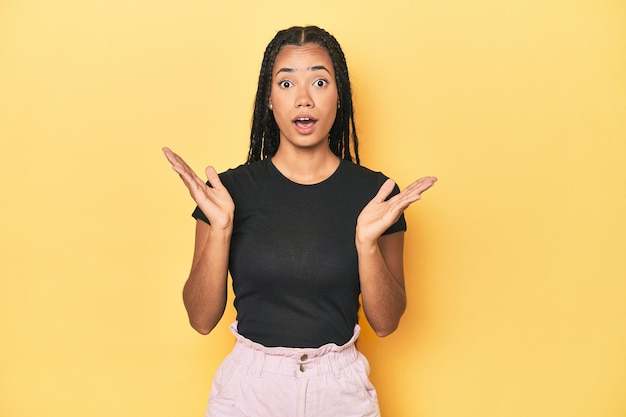 Young indonesian woman on yellow studio backdrop surprised and shocked