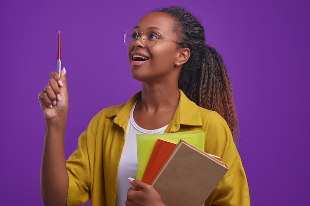 Photo young inspired african american woman student with textbooks raises pen up