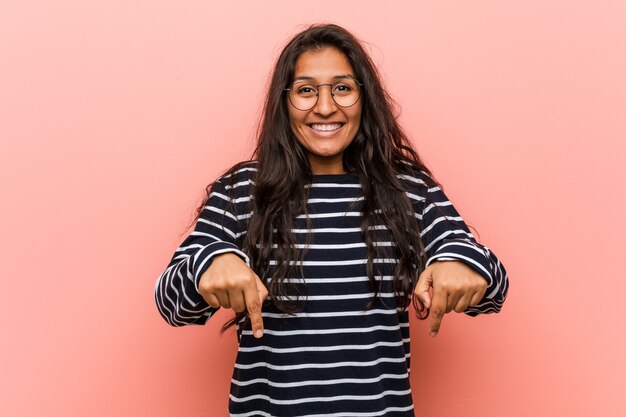 Photo young intellectual indian woman points down with fingers, positive feeling.