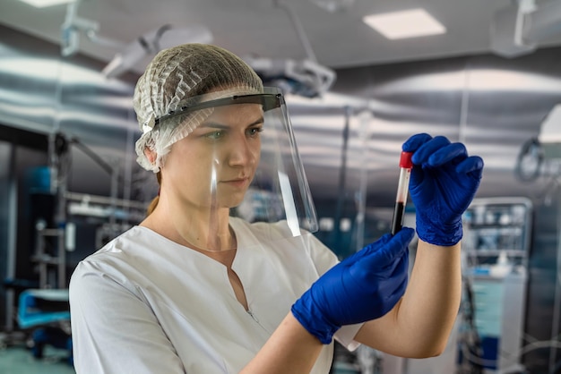 Young interesting doctor nurse woman holding and looking at a test tube with blood blood sampling of patients medicine