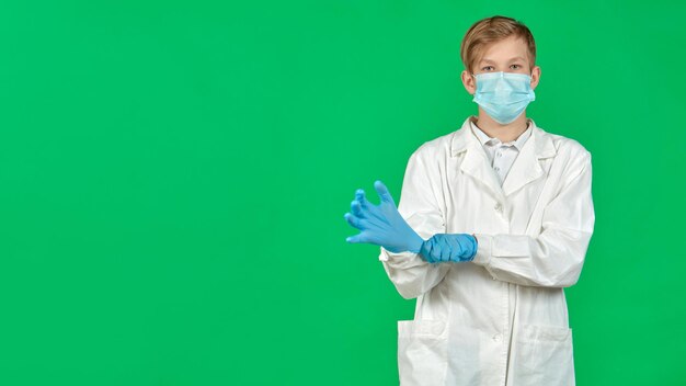 A young intern in a mask puts on gloves