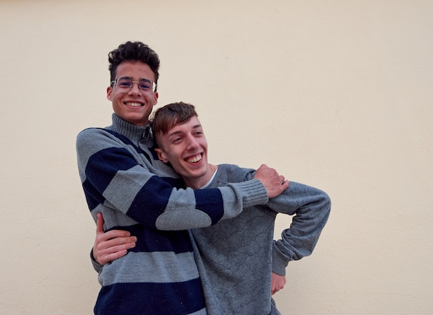 Photo a young interracial gay couple happily hugging isolated on a beige background