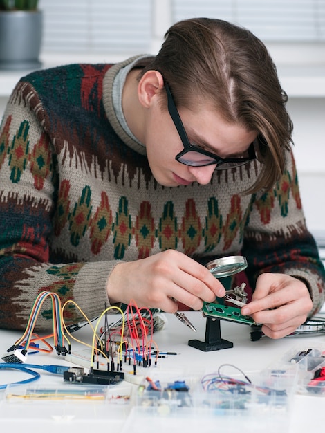 Foto giovane inventore esaminando componente elettronico.