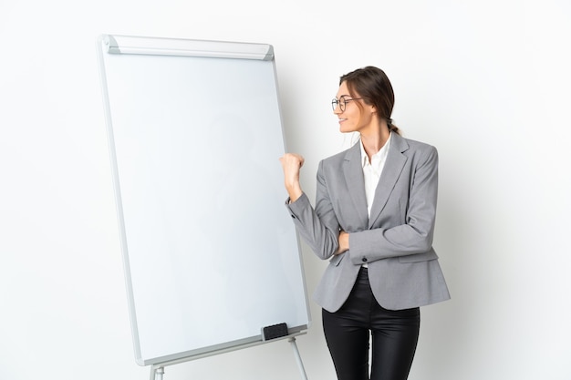 Young Ireland woman isolated on white background giving a presentation on white board and pointing to the side