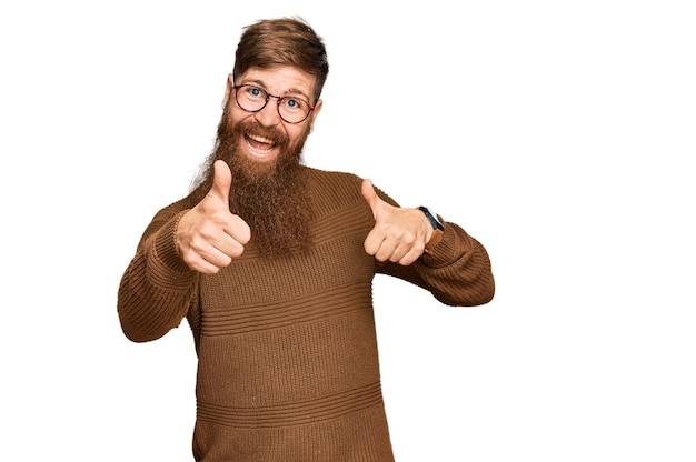 Young irish redhead man wearing casual clothes and glasses approving doing positive gesture with hand thumbs up smiling and happy for success winner gesture