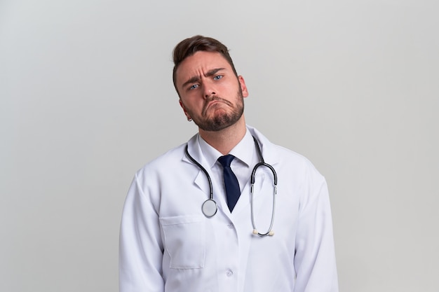 Young ironic handsome caucasian doctor on white background