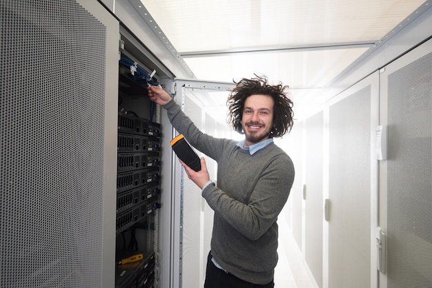 Photo young it technician using digital cable analyzer on server in large data center