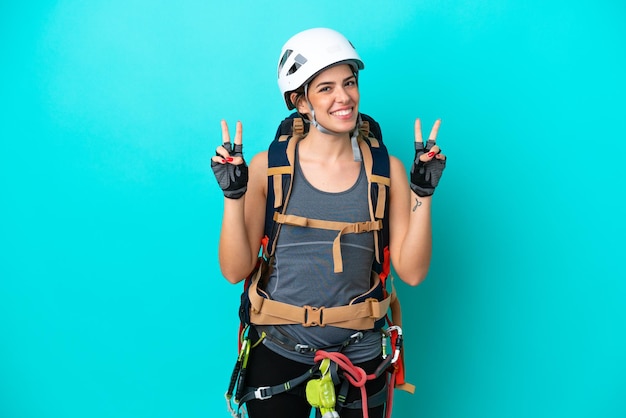 Young Italian rock-climber woman isolated on blue background showing victory sign with both hands