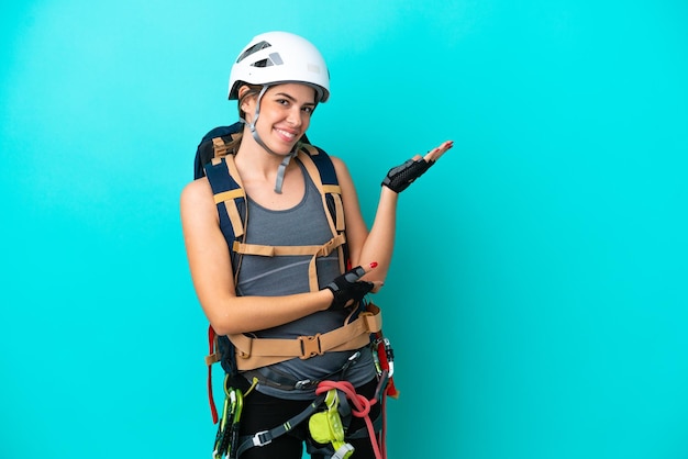 Young Italian rockclimber woman isolated on blue background extending hands to the side for inviting to come