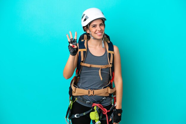 Young Italian rockclimber woman isolated on blue background happy and counting three with fingers