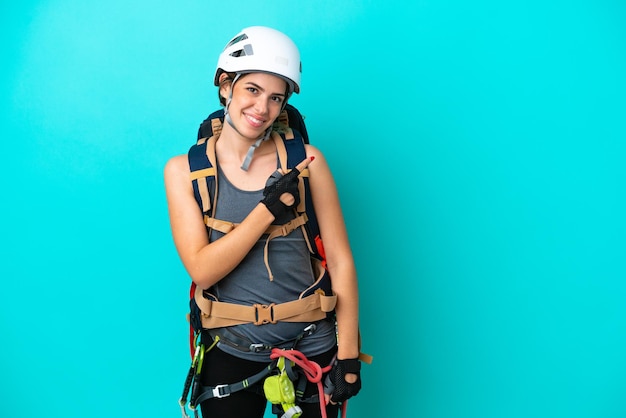 Young Italian rockclimber woman isolated on blue background pointing to the side to present a product