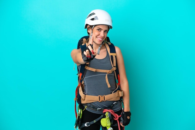 Giovane donna italiana rockclimber isolata su sfondo blu che mostra e alza un dito