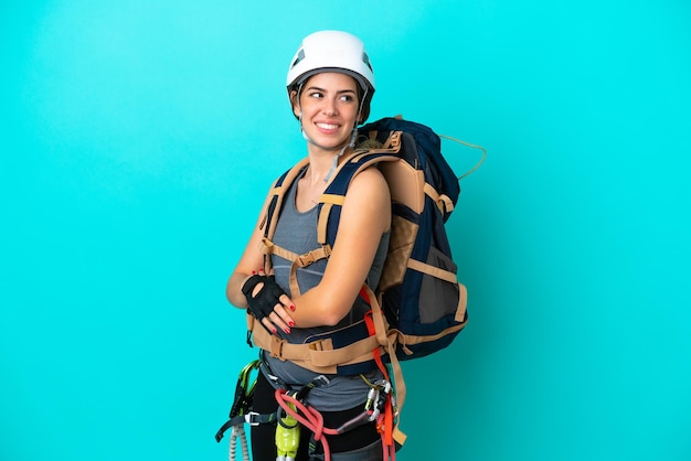 Young Italian rockclimber woman isolated on blue background with arms crossed and happy