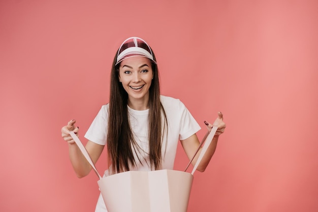 Young Italian woman with long hair in a white Tshirt colored transparent visor holds open bag