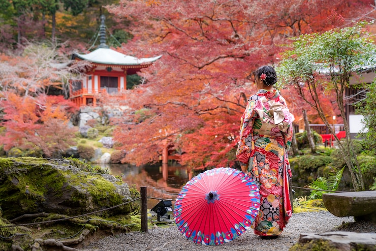 京都の秋の紅葉と赤いカエデの葉のディゴ寺に立っている伝統的なキミノドレスの若い日本の女の子の旅行者。