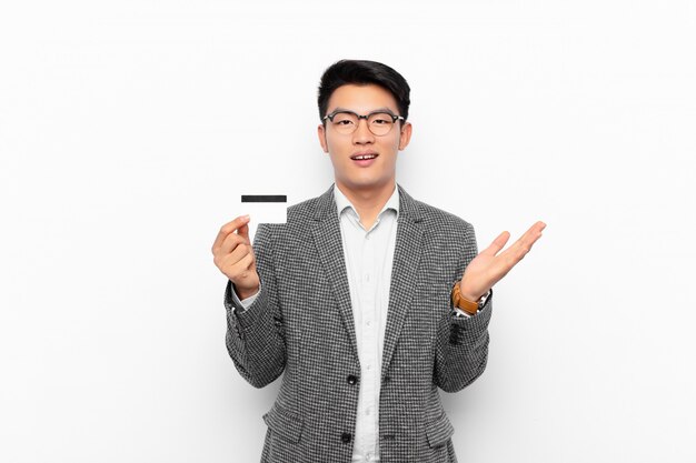 young japanese man feeling happy, surprised and cheerful, smiling with positive attitude, realizing a solution or idea. credit card concept.