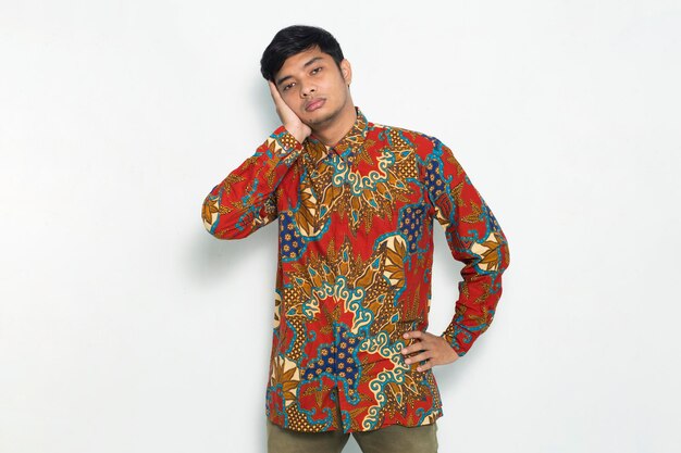 Young javanese man wearing batik feeling tired  isolated on white background